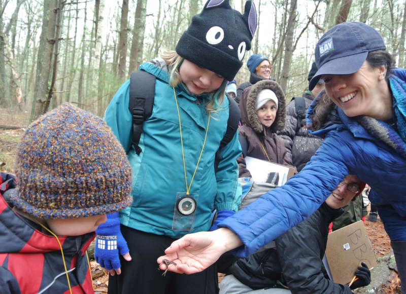 environmental educator showing a frog to a boy in the woods