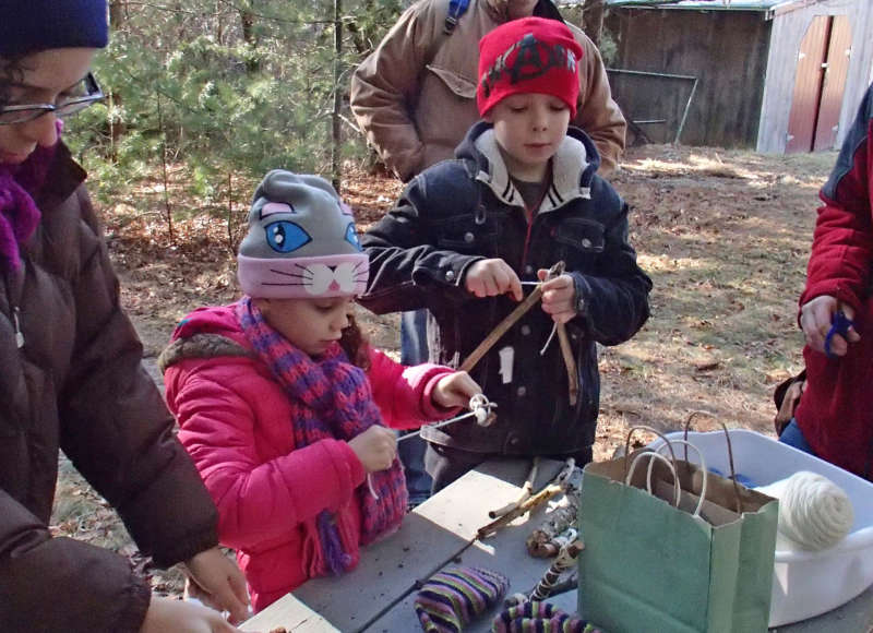 kids using sticks to create a craft in the woods