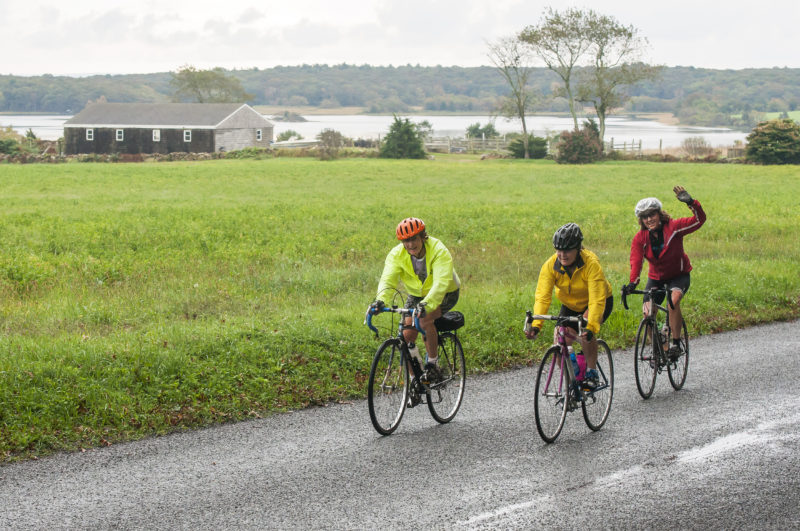three women bike riding in South Dartmouth past the Slocums River