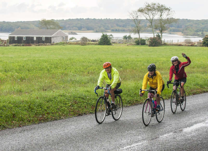 three women bike riding in South Dartmouth past the Slocums River