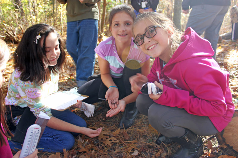 three East Fairhaven Elementary School students find a salamander on the nature trail behind their school