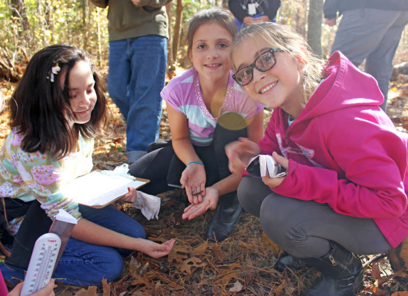three East Fairhaven Elementary School students find a salamander on the nature trail behind their school