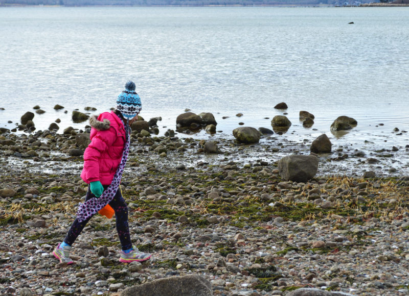 a girl walks on Little Harbor Beach in winter