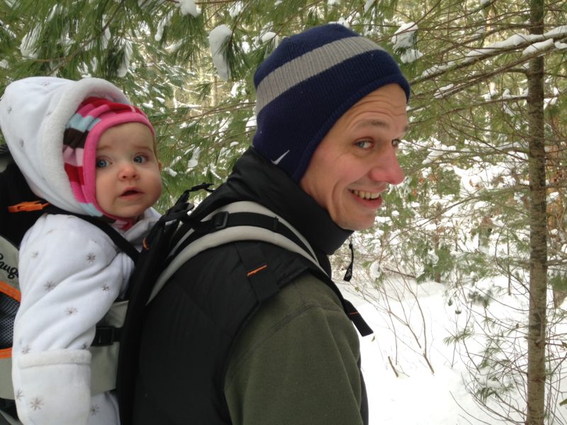 father with baby daughter hiking in the snow