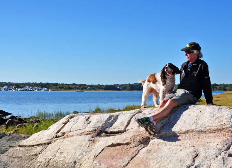 a man and a dog on a large rock at the Munn Preserve in Mattapoisett