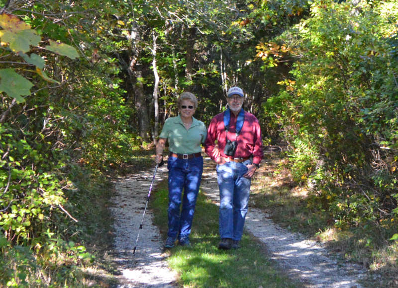 a couple walking through the woods on the trail at the Munn Preserve in Mattapoisett