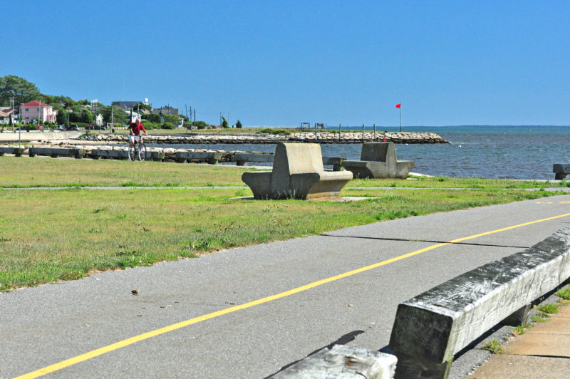 man riding a bike past the water on the Saulnier Memorial Bike Trail in the South End of New Bedford