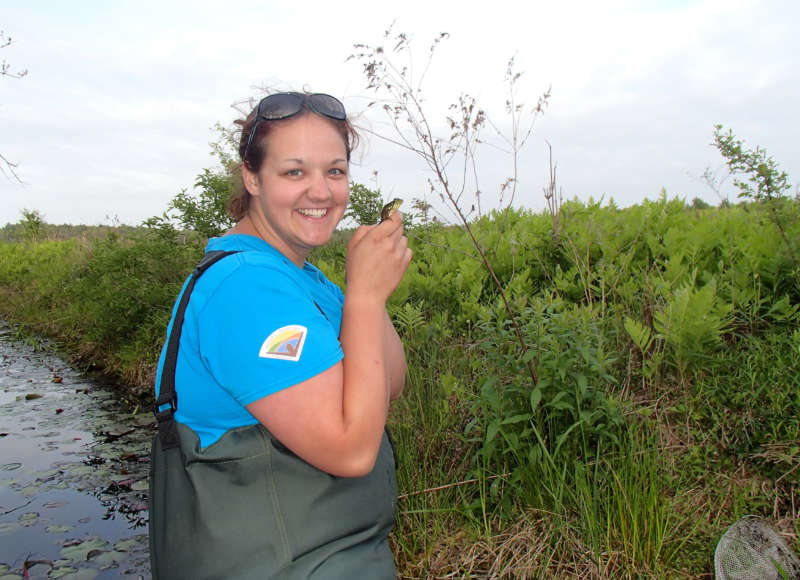 a woman in waders holding a frog at The Bogs in Mattapoisett