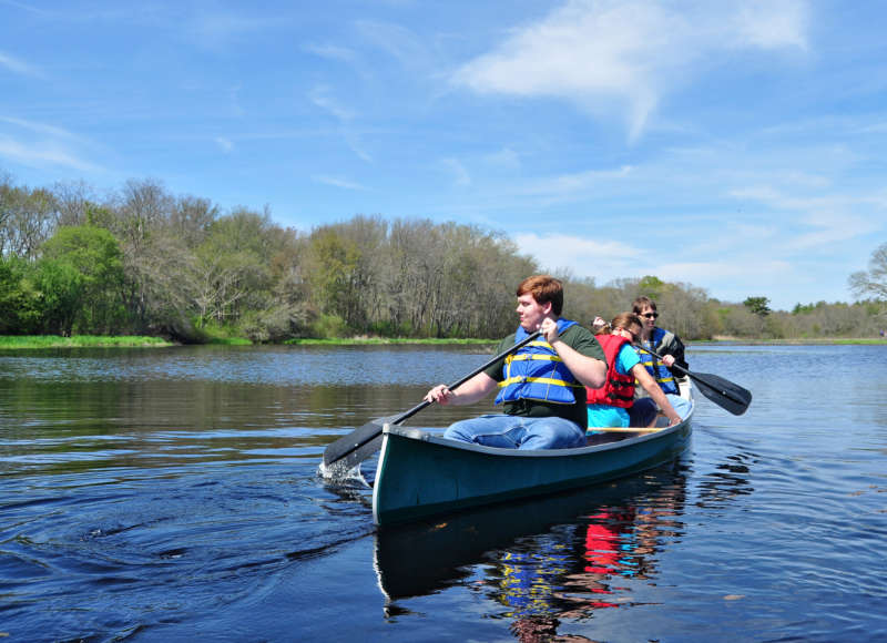 a family canoeing in the Acushnet River at The Sawmill