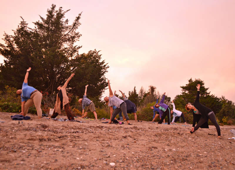 a group of people doing yoga at sunset on the beach in Mattapoisett