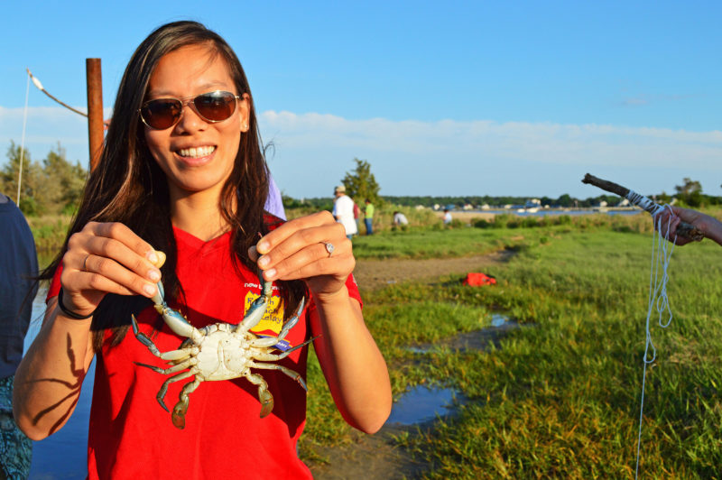 woman holding a blue crab at Eel Pond in Mattapoisett