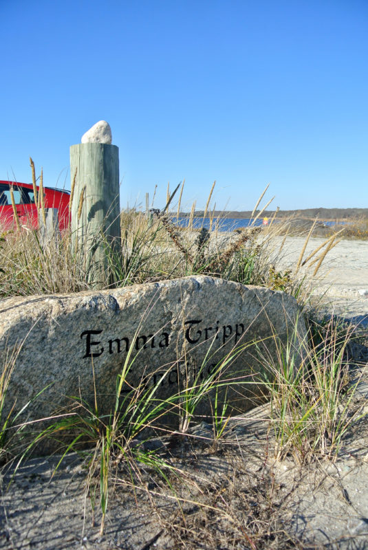 A stone inscribed with Emma Tripp Landing's name in front of a parking lot