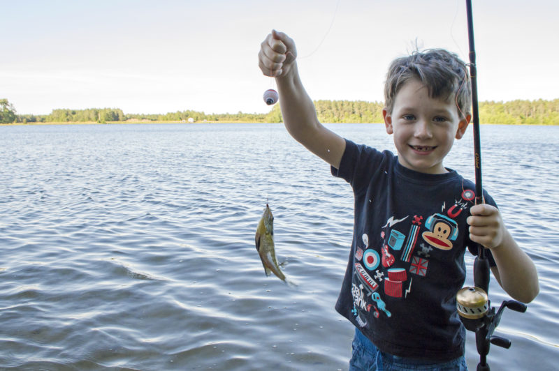 boy holding up a fish he caught in Mary's Pond in Rochester