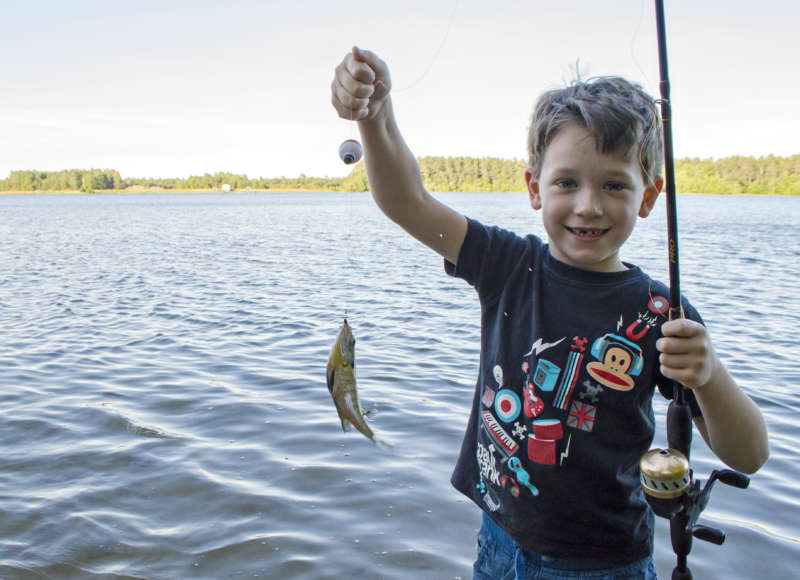 boy holding up a fish he caught in Mary's Pond in Rochester