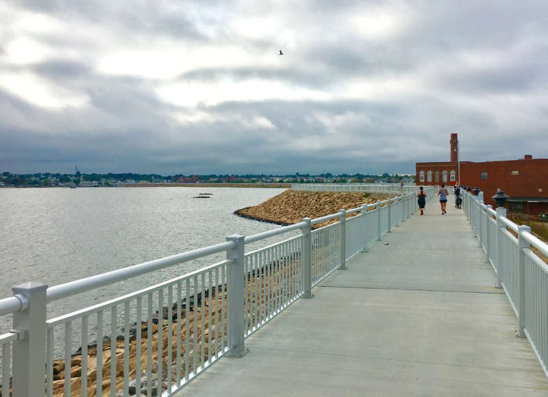 People walking and jogging on the New Bedford CoveWalk.