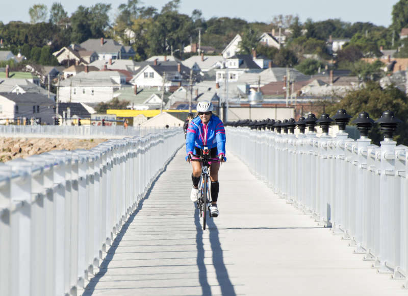 A woman riding her bike on the New Bedford CoveWalk during the Buzzards Bay Watershed Ride.