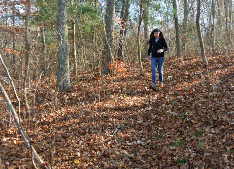 A woman walking down a wooded trail at Cataumet Greenway in Bourne.