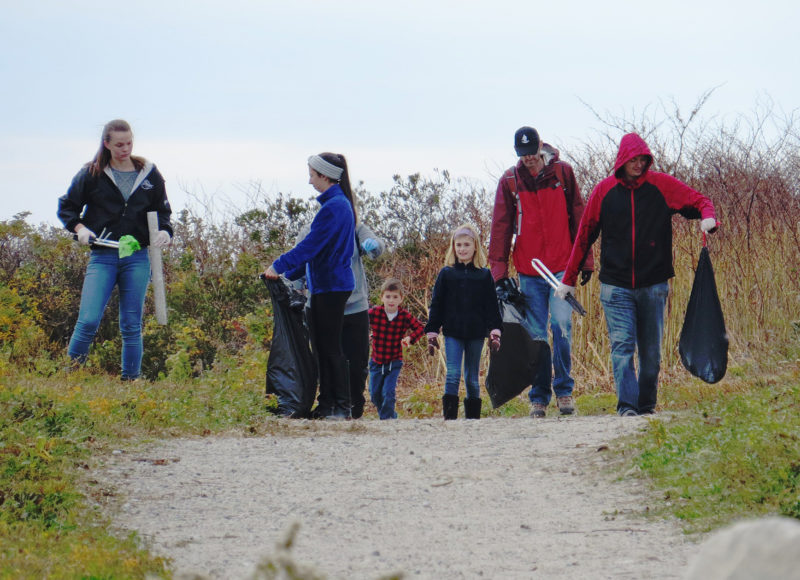 People carrying bags of trash at a cleanup at Gooseberry Island in Westport.