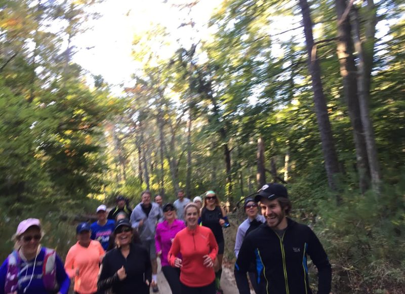 Trail runners in a group running through the woods.