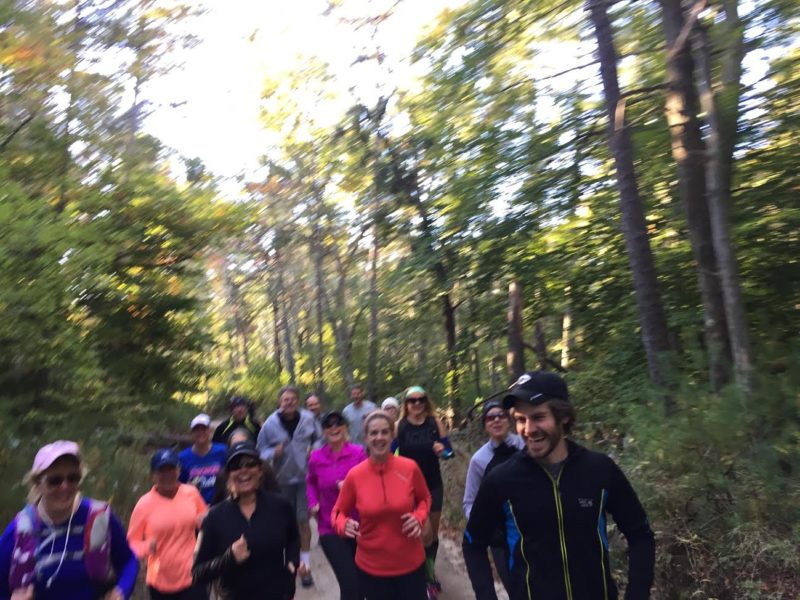 Trail runners in a group running through the woods.