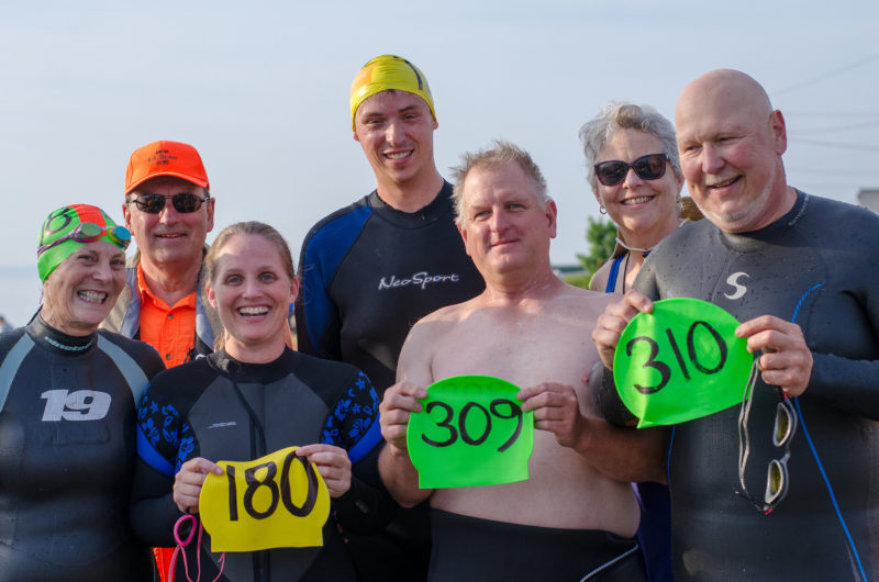 Men and women holding swim caps at the start of the Buzzards Bay swim.