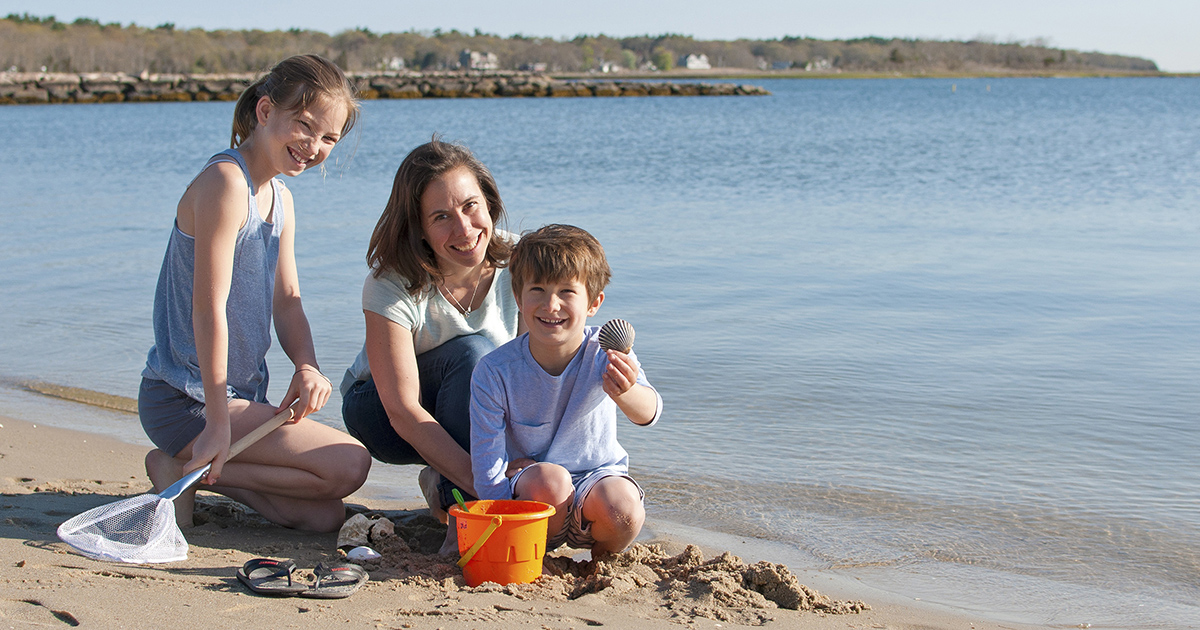A family sitting on Silvershell Beach in Marion