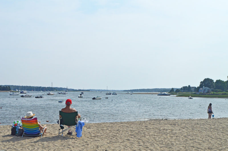 Two people in beach chairs looking out at Hen Cove in Bourne