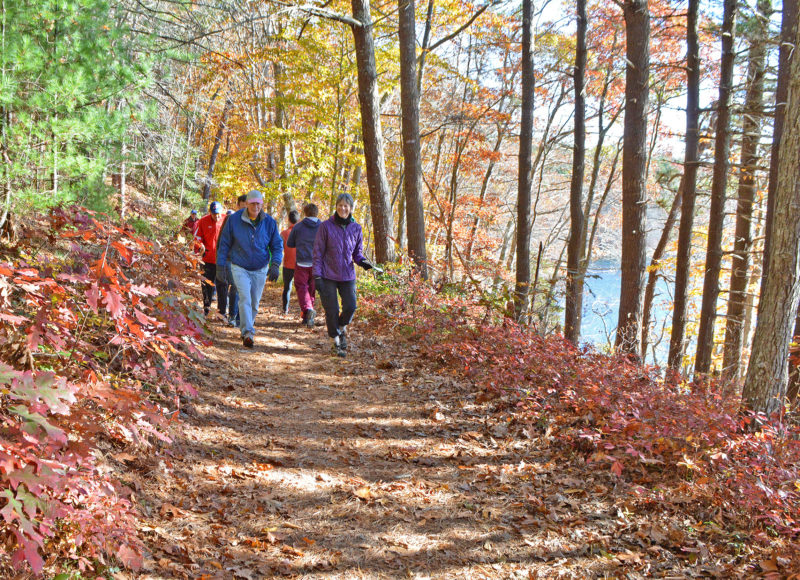 A group of hikers on the trail beside Long Pond during the fall