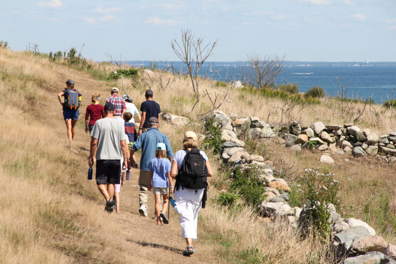 A group of people walking on Penikese Island with a view of Buzzards Bay