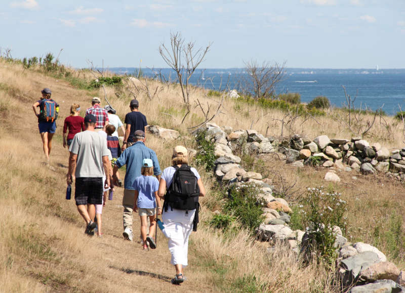 A group of people walking on Penikese Island with a view of Buzzards Bay