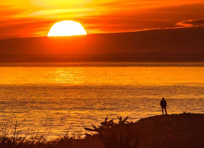 A person watches a brilliant orange sunrise in Westport
