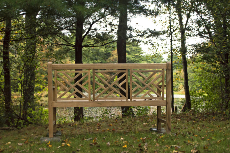 Wooden bench at the edge of a tree-lined pond in Gidley Woods in Dartmouth