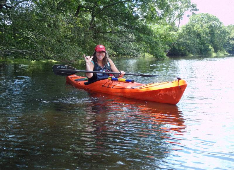 Samantha Ladd in a kayak beneath a tree overhanging a river