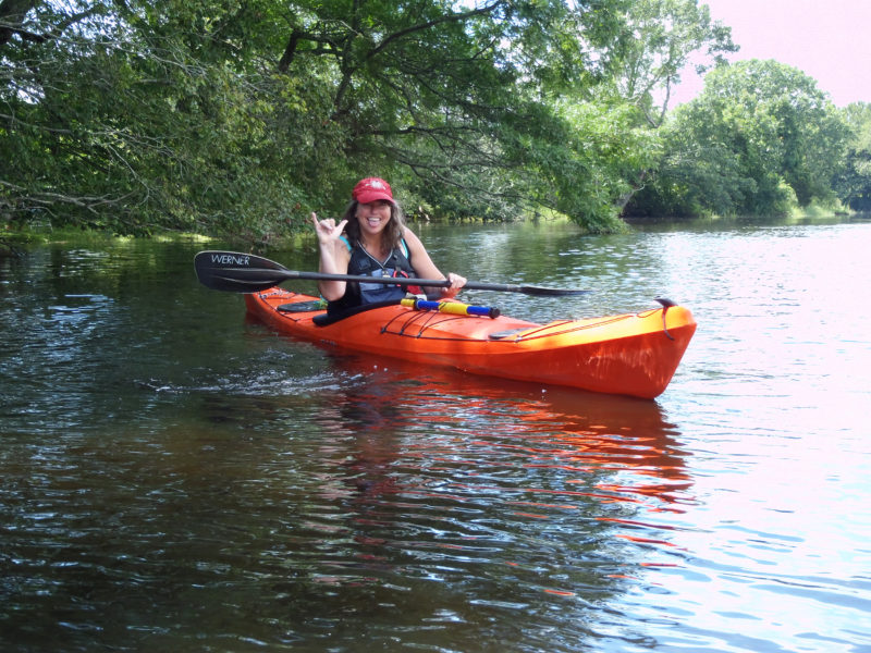 Samantha Ladd in a kayak beneath a tree overhanging a river