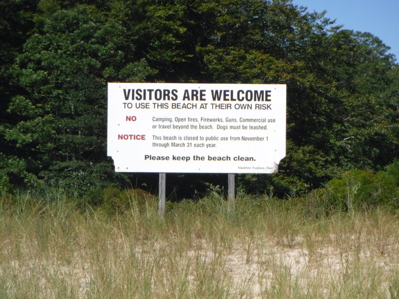 A sign at Tarpaulin Cove welcoming visitors and explaining the rules of the public beaches