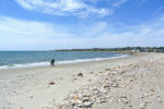 Two people walking along the water's edge at South Shore Beach in Little Compton