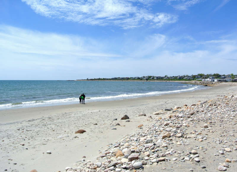 Two people walking along the water's edge at South Shore Beach in Little Compton