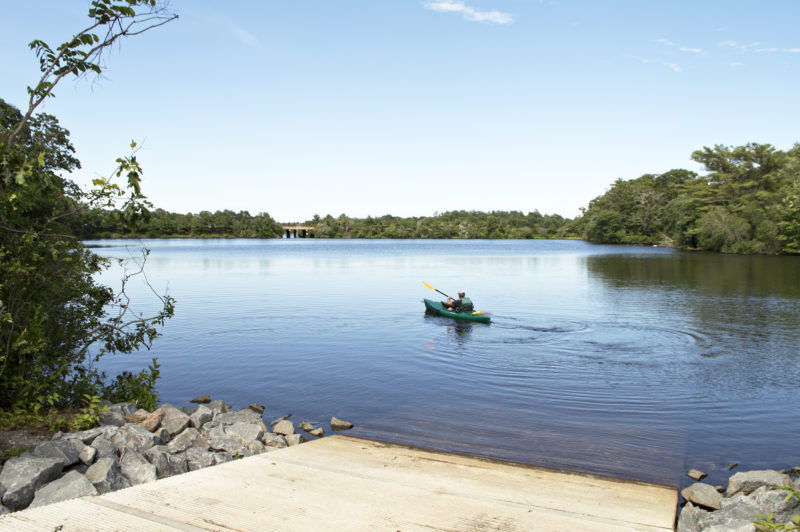 A man paddling a kayak away from the Agawam Mill Pond Boat Launch in Wareham