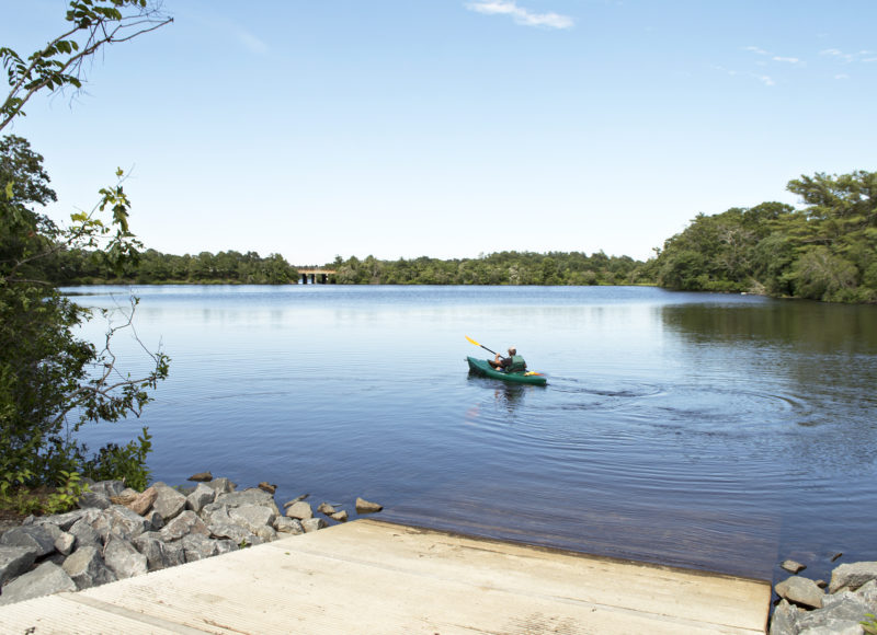 A man paddling a kayak away from the Agawam Mill Pond Boat Launch in Wareham