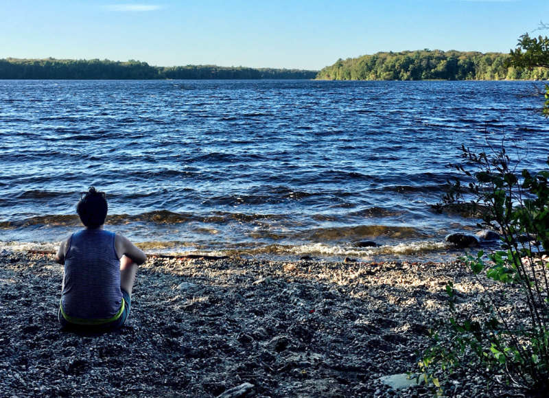 A woman sitting by the edge of Great Quittacas Pond at New Bedford Waterworks in Rochester.