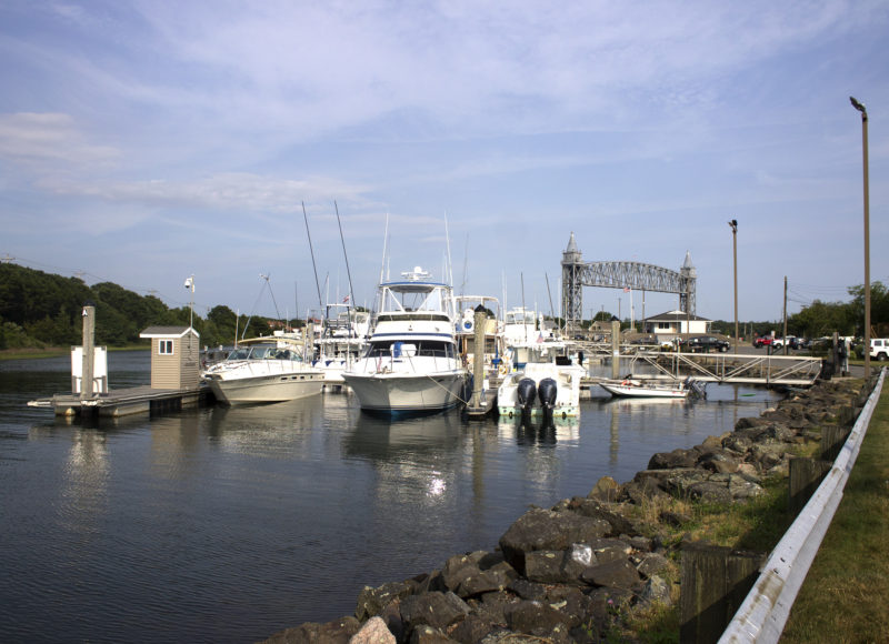 Boats tied up at Taylor Point Marina with a view of the Cape Cod Canal railroad bridge