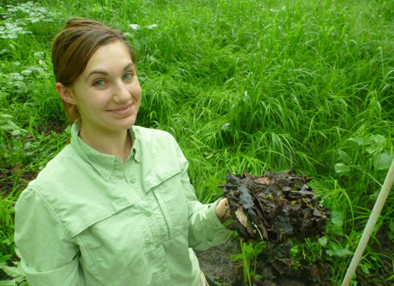 A woman in a green shirt holding up a square of mud