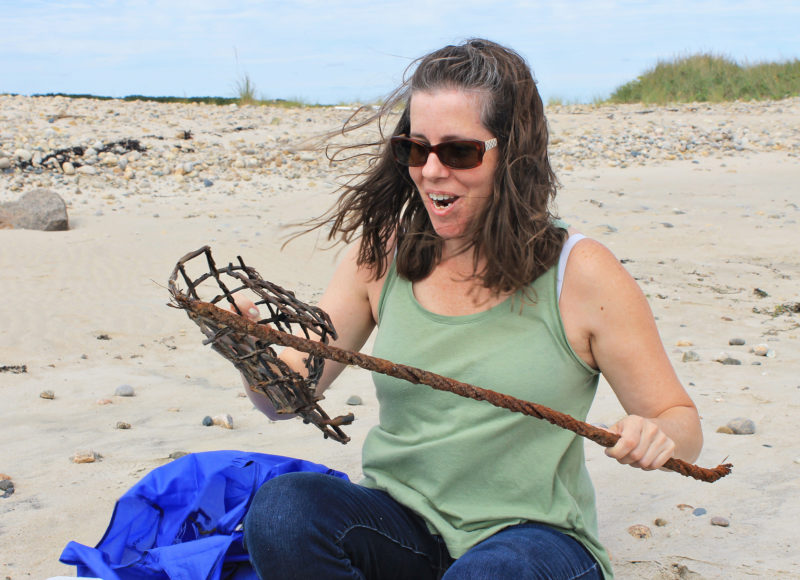 A woman on a beach looking at some pieces of metal