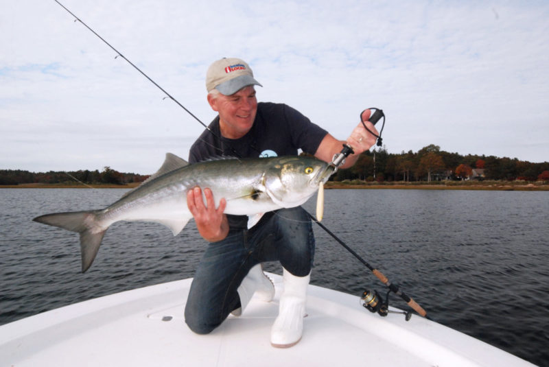 Tom Richardson on the bow of a boat displaying a large hooked bluefish