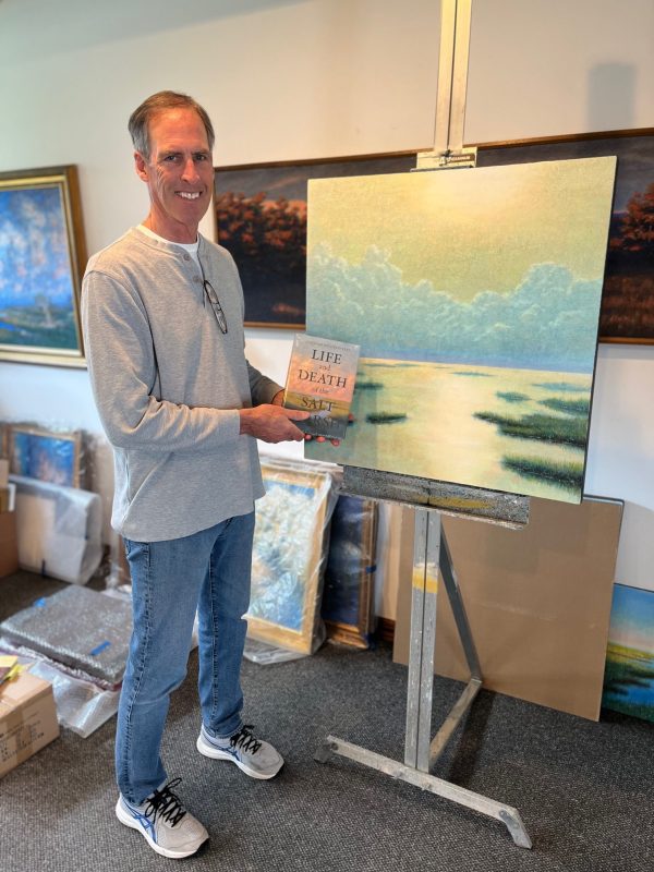 Artist and author Peter Stone holds the book, which features his artwork on the cover.
