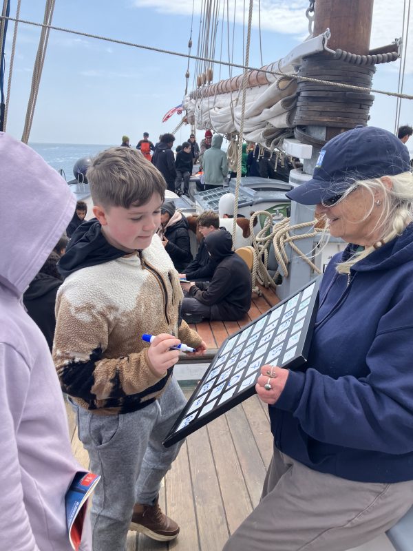 Lynn Connor helps a sixth grader record water data from their onboard testing.