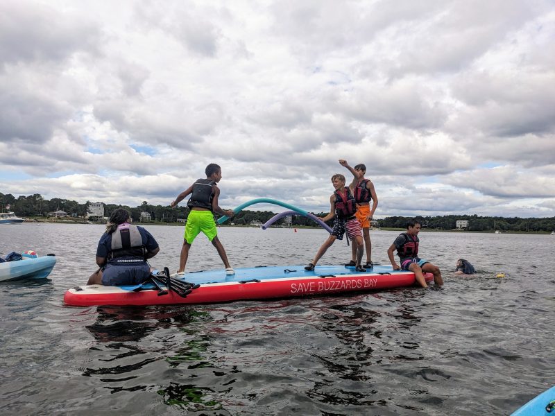Campers duel with Styrofoam noodles on a paddleboard.